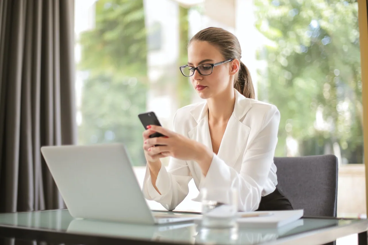 Ragazza property manager che controlla al telefono prenotazioni su Airbnb